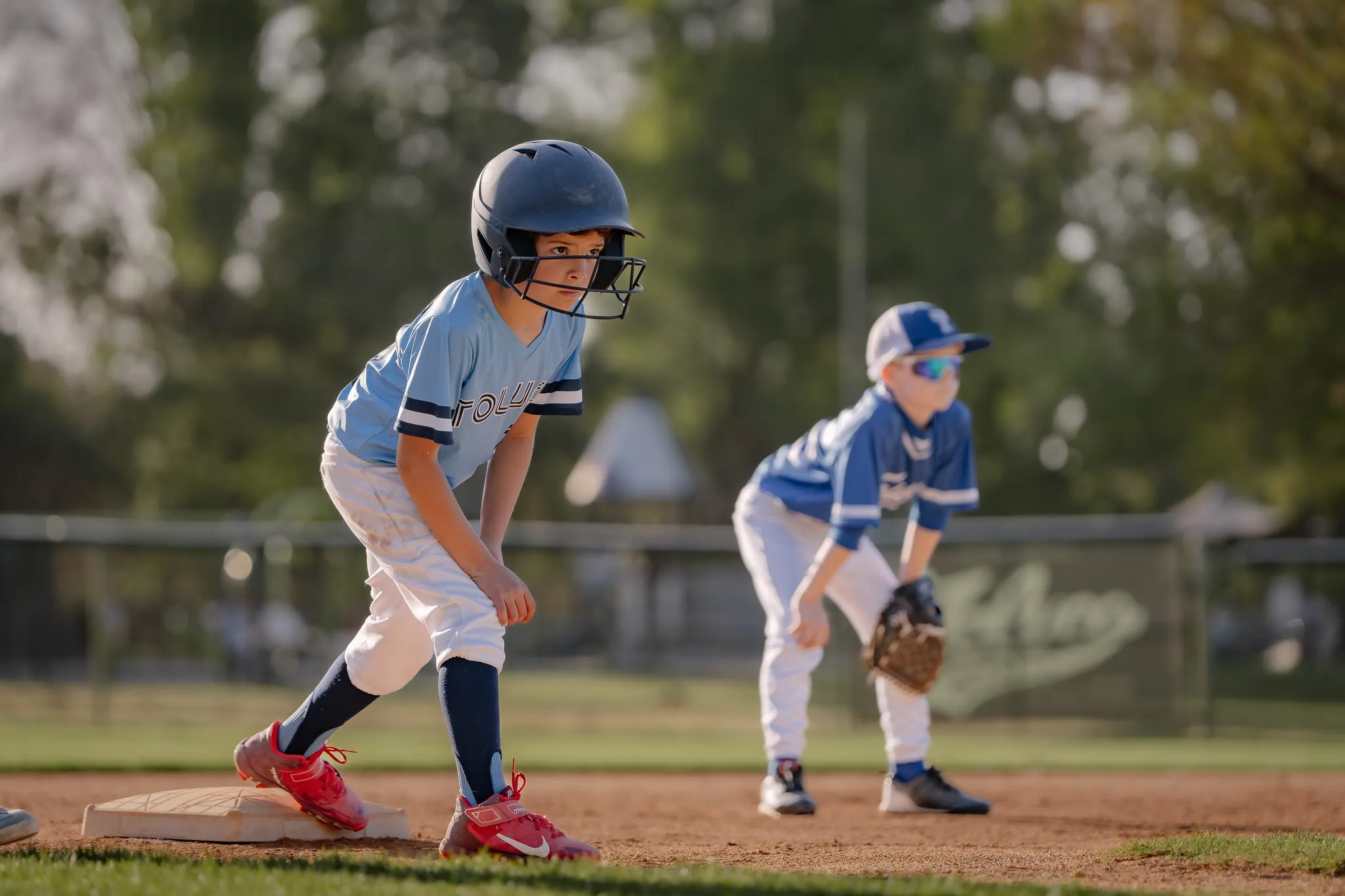Base runner takes his lead off the bag as the infielder crouches behind