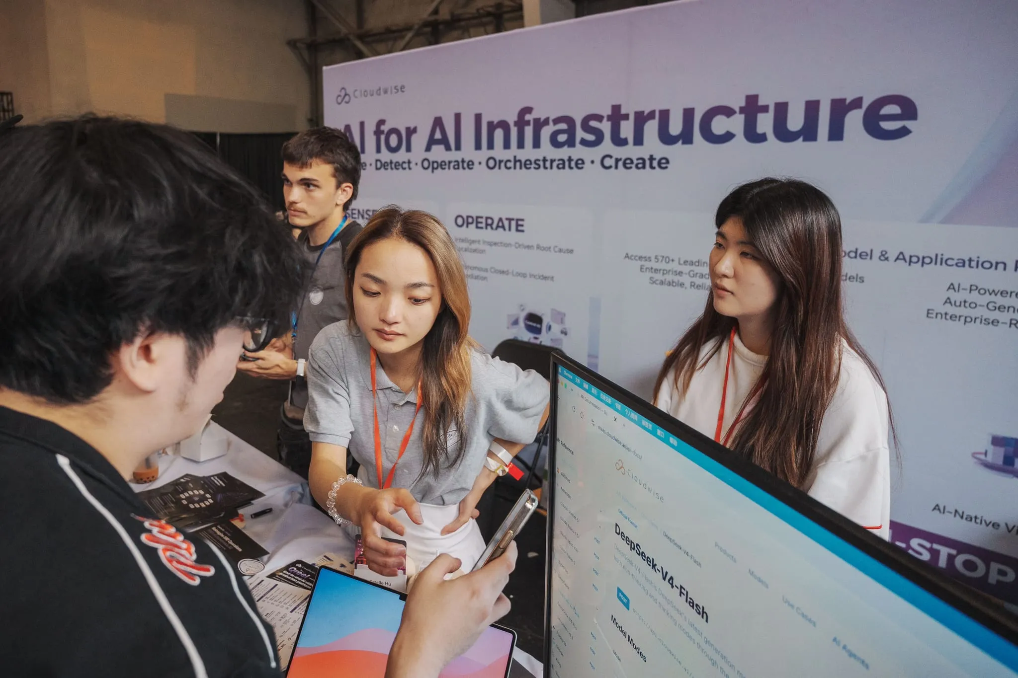 Booth staff walk a visitor through a live product demo at a tech expo