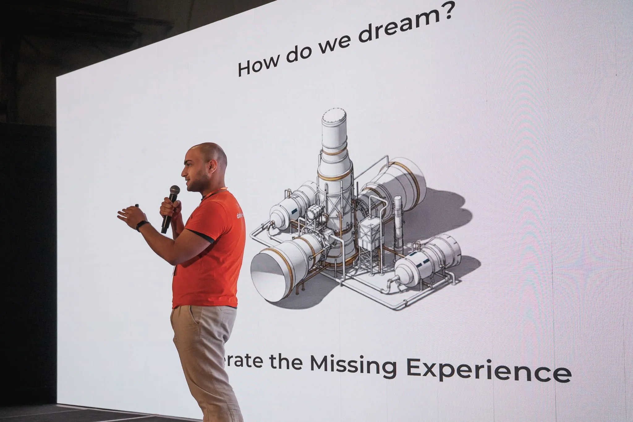 A speaker presents against a wall-sized LED screen on the expo main stage